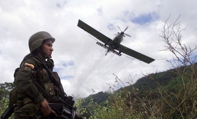 A Colombian soldier patrols an area being aerially fumigated
