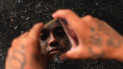An alleged Honduras gang member looking at his reflection