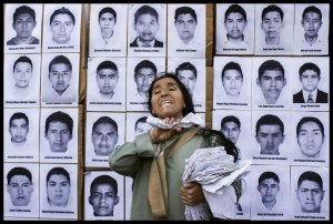 A protester stands in front of pictures of the disappeared students