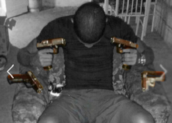 Un pandillero posa con la cabeza agachada mientras sujeta una pistola en cada mano