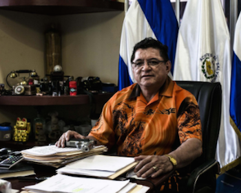 Catalino Mirando, owner of Acostes bus company, poses with his 9 mm pistol in his office.