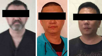 The recently detained migration official, left, and two Chinese nationals