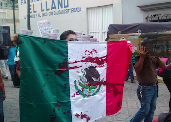 Protester carrying a blood-soaked Mexican flag