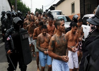 Gang members guarded by policemen outside El Salvador prison