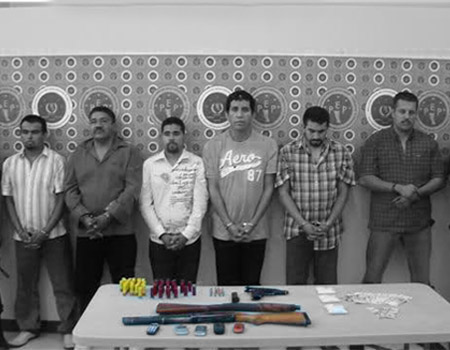 Members of the Tijuana Cartel stand in front of weapons