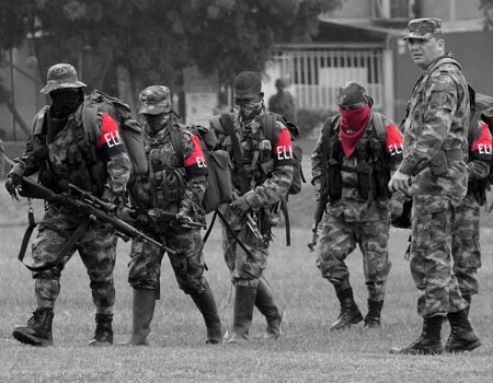 Un grupo de cinco guerrilleros con brazaletes del ELN marchando con sus armas