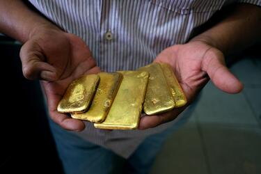 A man holds several gold bars coming from conflict zones