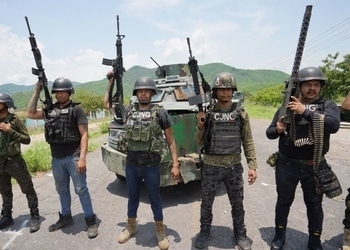Five members of the Jalisco Cartel stand in front of a heavily armored truck, holding up automatic rifles.