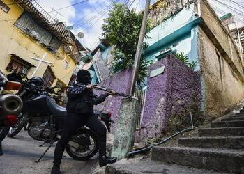 A member of Venezuela's CICPC force with his gun drawn out in Petare, east of Caracas
