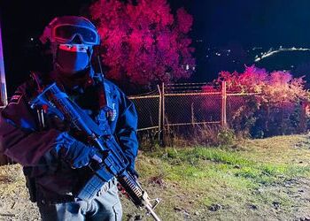 A Mexican soldier stands guard outside the ranch where 20 people were killed in Michoacan