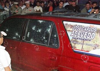 A crowd looks at the car of Pedro Juan Caballero mayor, José Carlos Acevedo, after the attempted hit on his life as crime in Paraguay rockets