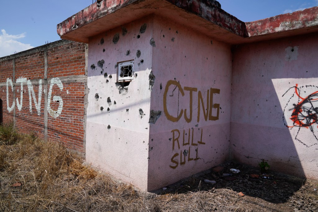 The initials of the Jalisco Cartel New Generation (CJNG) are painted on a building riddled with bulletholes in Michoacan, Mexico