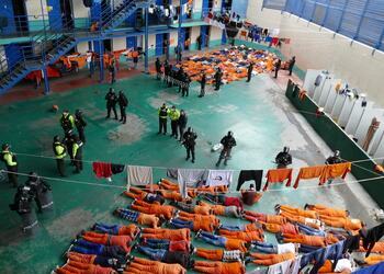 Prisoners lay on the floor with their hands on their heads as Ecuadorian secutiry forces regain control of the prison pavillion