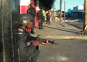 A Jamaican soldiers stands, rifle in hand, close to the camera while on patrol in Kingston, Jamaica