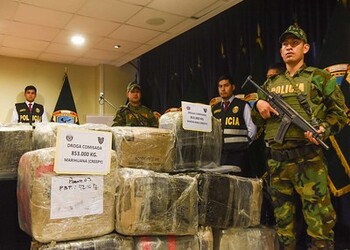 Members of the National Police of Peru are shown armed next to a creepy marijuana seizure