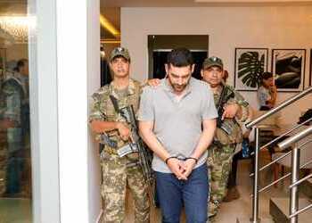 Rodrigo Alvarenga, a presumed leader of the group targeted by Operation Hinterland, stands between Paraguayan authorities after being arrested.