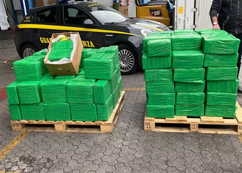 Incautación de cocaína en unas cajas de bananas, recubiertas de plástico verde, con un coche de la policía italiana en el fondo