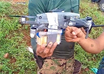 Two men holding a drone modified to carry explosives in Mexico.