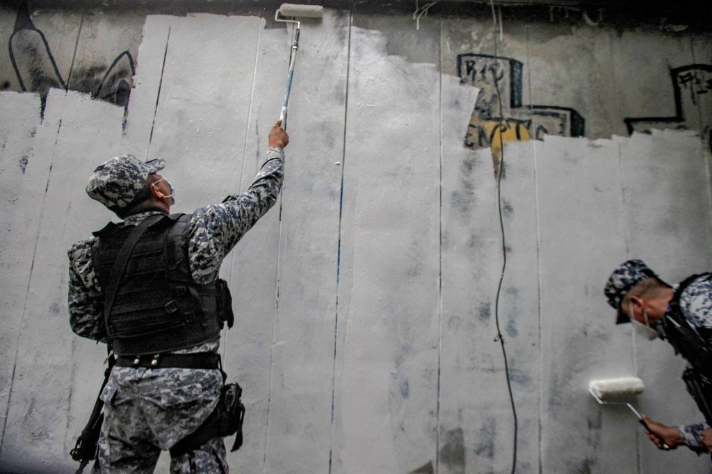 Salvadoran security forces whitewashing a wall.