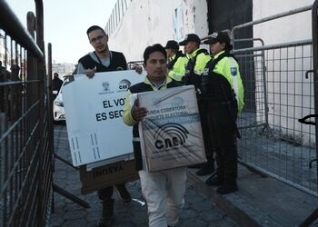 Dos funcionarios cargan las urnas de votación en Ecuador