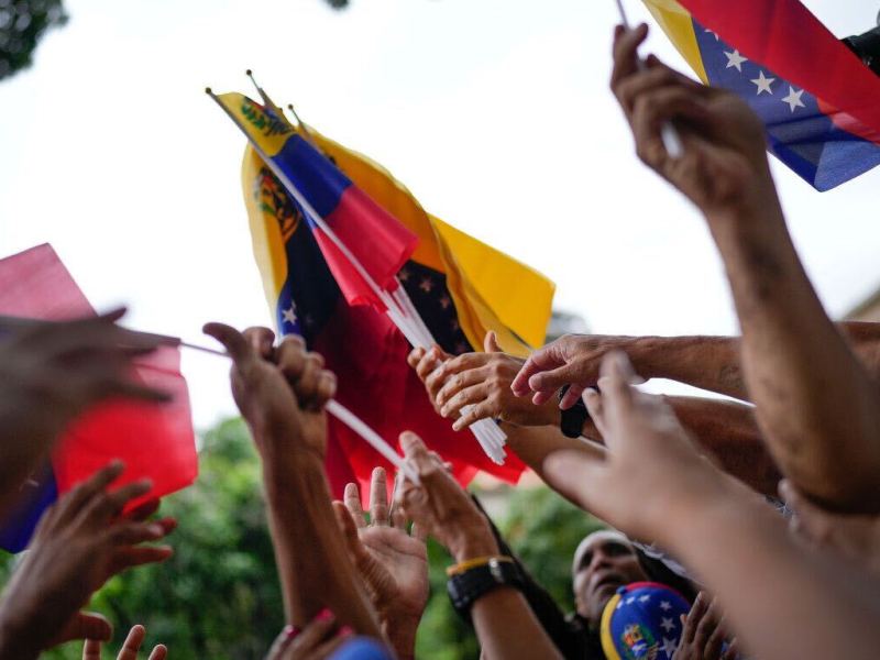 The flag of Venezuela being waved at a political event.