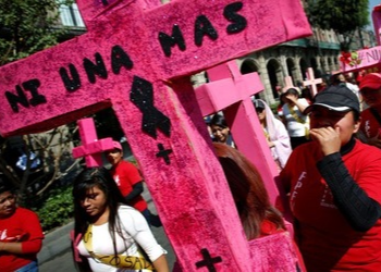 Mujeres portan cruces rosas que dicen “ni una más” en una protesta contra la violencia de género en la Ciudad de México.