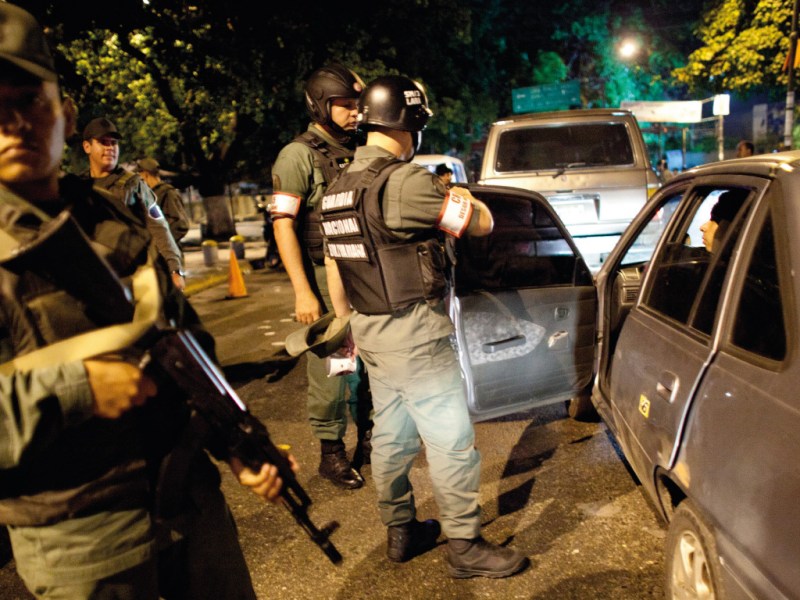 Police officials stop a driver at a checkpoint in Venezuela
