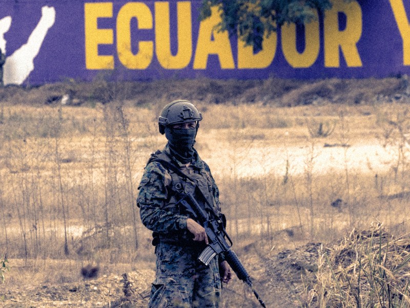 A soldier stands in front of an electoral poster for President Daniel Noboa.