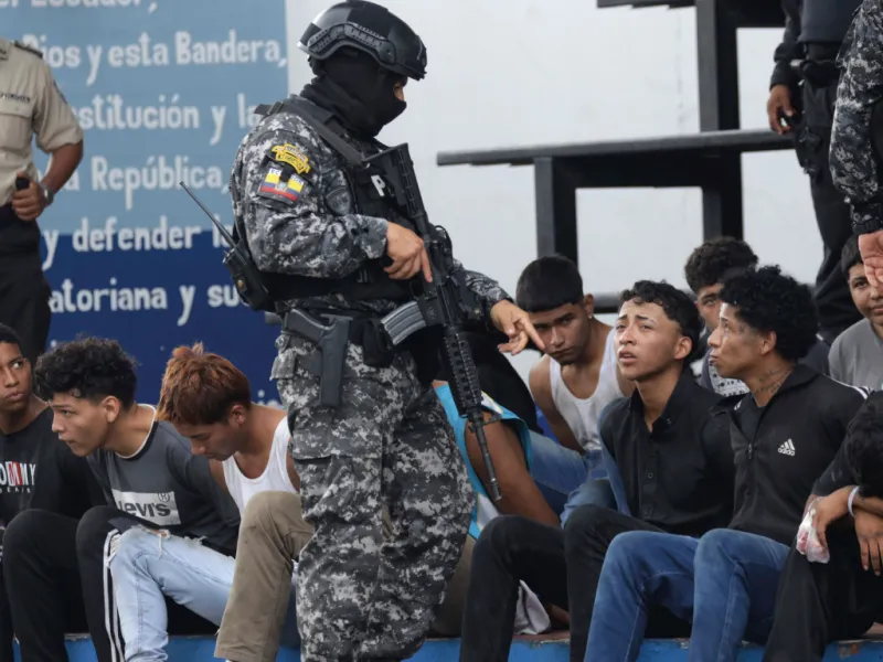 Un soldado ecuatoriano frente a una fila de hombres detenidos.
