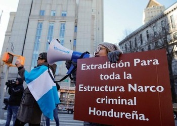 Protesters hold signs calling for extradition for all members of the "Honduran criminal narco structure." Manifestantes sostienen carteles que piden la extradición de todos los miembros de la "estructura narco criminal hondureña".