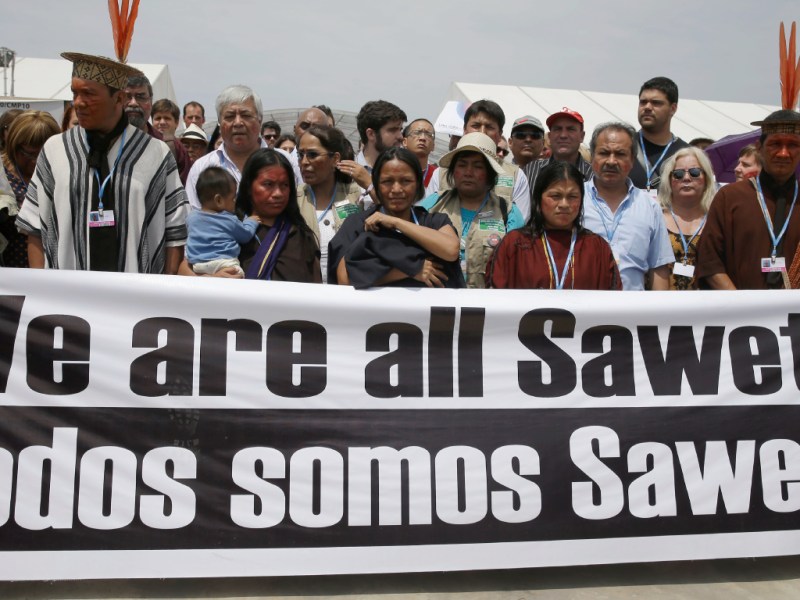 The widows of the Saweto murder victims walk behind a banner at the 2014 Climate Change Conference in Lima, Peru.