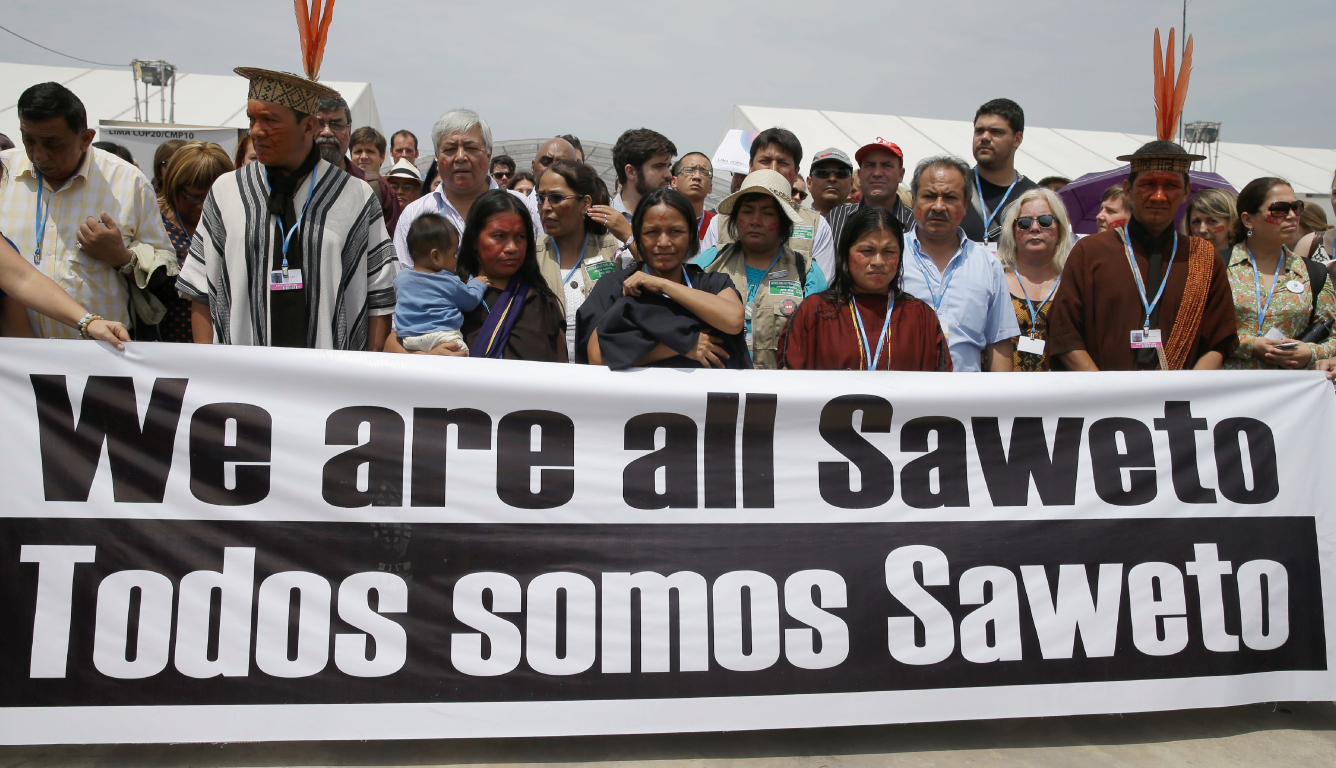 The widows of the Saweto murder victims walk behind a banner at the 2014 Climate Change Conference in Lima, Peru.
