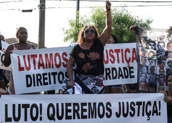 Protesters hold signs calling for justice in a march against civilian deaths under Operation Shield, in Baixada Santista. Manifestadores con avisos pidiendo justicia en una manifestación contra las muertes provocadas por la Operación Escudo, en la Baixada Santista.