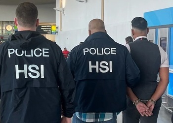 Authorities escort a flight attendant accused of smuggling money out of the US and into the Dominican Republic from JFK airport. 
Las autoridades escoltan