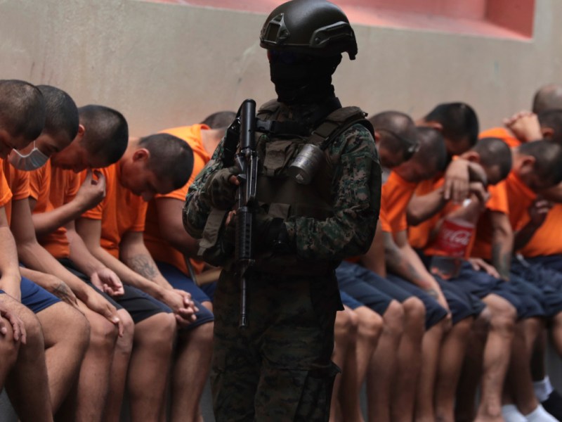 Ecuadorian soldier stands guard over a line of prisoners. Un soldado ecuatoriano patrulla una fila de prisioneros.